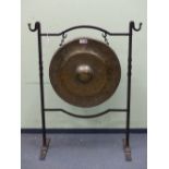 A BELL METAL GONG ON A WROUGHT IRON STAND, THE HOOK TOPPED UPRIGHTS JOINED BY TWO SERPENTINE