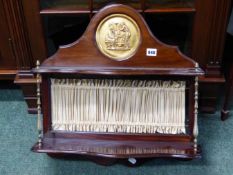 AN EDWARDIAN MAHOGANY WALL SHELF, THE BACK TOPPED BY A CLASSICAL GILT METAL ROUNDEL OVER TWO SHELVES