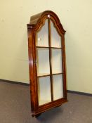 A WALNUT CORNER CABINET, THE ARCHED TOP OVER A DOOR GLAZED WITH SIX PANELS AND ENCLOSING THREE