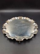 A SILVER HALLMARKED CIRCULAR FORM SALVER ON THREE FEET WITH A CHIPPENDALE STYLE BORDER, PRESENTATION