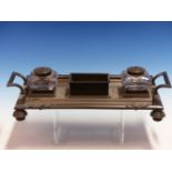 A PLATED TWO HANDLED INKSTAND, THE CENTRAL TROUGH FLANKED BY TWO GLASS INKWELLS, THE TWO PEN TROUGHS