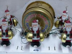 SANTA'S GRAND MARCHING BAND OF FIVE SANTA CLAUS FIGURES EACH BEATING TWO BRASS BELLS.