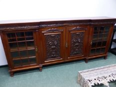 A MAHOGANY BREAKFRONT BOOKCASE BY MAPLE & CO. THE CENTRAL BROKEN ARCH PEDIMENT ABOVE A TABLET