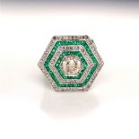 A WHITE METAL, EMERALD AND DIAMOND GEOMETRIC GRAIN SET CLUSTER RING. THE CENTRAL DIAMOND