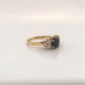 AN 18ct GOLD HALLMARKED SAPPHIRE AND DIAMOND RING. THE CENTRAL SAPPHIRE IN A SIX CLAW SETTING SET