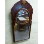 AN ARCHED MIRROR IN A WALNUT FRAME THE SHAPED TOP CENTRED BY A GILT SHELL. H 80 x 38cms.