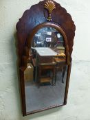 AN ARCHED MIRROR IN A WALNUT FRAME THE SHAPED TOP CENTRED BY A GILT SHELL. H 80 x 38cms.