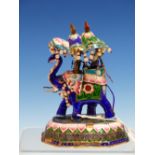 TWO INDIAN ENAMEL ELEPHANTS BEARING JEWELLED HOWDAHS AND WALKING ON STYLISED LOTUS FLOWER BASES. H