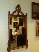 A RECTANGULAR MIRROR IN A GILT FRAME CRESTED BY A VASE OF FLOWERS AND SWAGS, THE BASE WITH