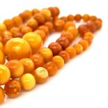 A GRADUATED CONTINUOUS ROW OF BUTTERSCOTCH AMBER BEADS, LENGTH APPROXIMATELY 64cms, WEIGHT 21.2grms.