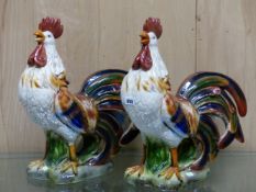 A PAIR OF COLOURFUL POTTERY CROWING COCKERELS. H 53cms.