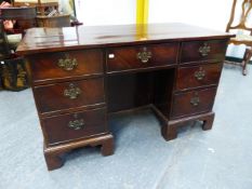 A MAHOGANY PEDESTAL DESK, THE QUARTER VENEERED TOP CROSS BANDED, THE CENTRAL APRON DRAWER ABOVE