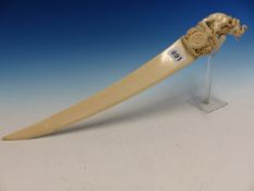 AN INDIAN IVORY PAGE TURNER WITH SCIMITAR BLADE, THE HANDLE CARVED WITH A LION ATTACKING AN