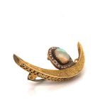 AN INDIAN FOLIATE ENGRAVED YELLOW METAL CRESCENT BROOCH, SURMOUNTED BY A D-SHAPED OPAL WITHIN A