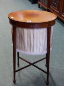 A MAHOGANY WORK TABLE, THE OVAL TOP CROSS BANDED AND OPENING ONTO A BEIGE PLEATED SILK WORK BAG