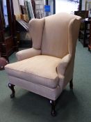 A MAHOGANY WING BACK ARMCHAIR, THE FRONT LEGS WITH PAD FEET