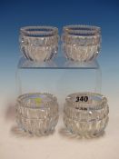 A SET OF FOUR ROUND CLEAR GLASS SALTS, THE SERRATED RIMS ABOVE ROUNDED SIDES WITH THE DEEP