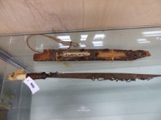 A DAYAK HEAD HUNTERS SWORD, THE WOODEN SCABBARD MOUNTED WITH BONE, THE SINGLE EDGED BLADE WITH