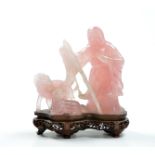 A finely carved pink quartz depicting playful rams and smiling shepherd. Wood stand. 19th century.