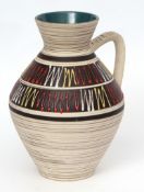 Austrian Pottery jug with single handle, decorated with an applied design in red, yellow and white