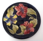 Large mid-20th century Moorcroft hibiscus charger with tube lined design on a blue ground, 31cms