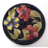 Large mid-20th century Moorcroft hibiscus charger with tube lined design on a blue ground, 31cms