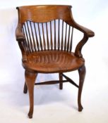 Early 20th century oak hard seated spindle back office armchair raised on pad feet, 65cms wide x
