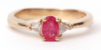 Modern ruby and diamond ring, the oval shaped faceted ruby raised between two small brilliant cut