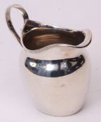 George V cream jug of helmet form with applied reeded rim and strap work handle, width 9 1/2cms,