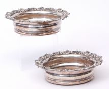 Pair of silver on copper bottle coasters each of compressed circular form with applied foliate