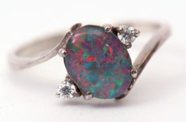 Opal cross-over ring, the central oval cut opal flanked by two brilliant white stones, stamped