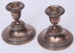 Two Elizabeth II squat candlesticks, each with fixed urn shaped sconces on spreading circular
