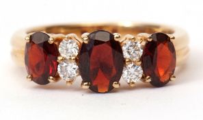 Garnet and diamond ring featuring 3 graduated oval garnets, having 4 small diamonds between, stamped