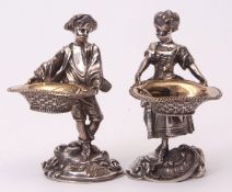 Two 20th century figural table salts, modelled in the form of a young man and lady each in 18th