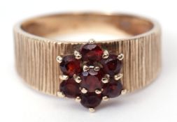 Vintage yellow metal and garnet cluster ring featuring a flower head of small garnets raised on