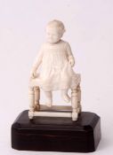 Early 20th century carved ivory model of a young child sitting upon a bobbin turned joint stool