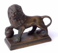 Cast brass model of a standing lion with right paw atop a sphere on a rectangular base, width 8 1/
