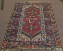 20th century Caucasian style wool rug, centre with three cruciform lozenges, mainly red, purple