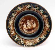 Austrian pottery charger with raised design of cherubs to centre and around border in various