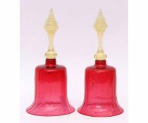 Two Victorian cranberry glass hand bells with tinted opaque handles, each 30cms high