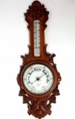 Late 19th century carved oak aneroid wheel barometer with carved and pierced foliate detail to a