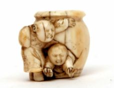 Late 19th/early 20th century ivory netsuke modelled as two children playing with a barrel, 3cms high