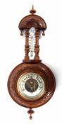 Early 20th century walnut cased aneroid wheel barometer, carved and shaped pediment over a twin-