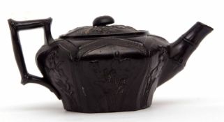 Pottery tea pot, the black ground decorated with panels containing applied flowers with bamboo style