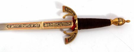 Two souvenir type daggers, each with gilt highlighted blades with brass cross-guards and cotton