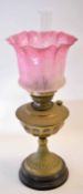 Brass oil lamp on black metal base with pink shade