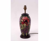 Moorcroft lamp base with a stylised tube lined design of anemones or hibiscus on a black oval