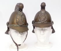 Two early 20th century French brass firemen's helmets, each with scrolling crest and riveted badge