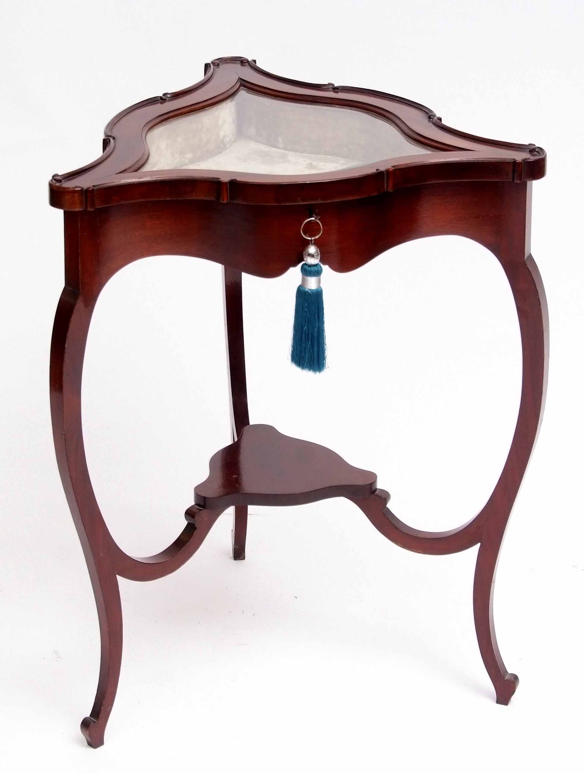 Mahogany bijouterie table of shaped triangular form, the lifting lid with central bevelled glass