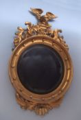 Early 19th century giltwood circular wall mirror, crested with eagles supported by foliate